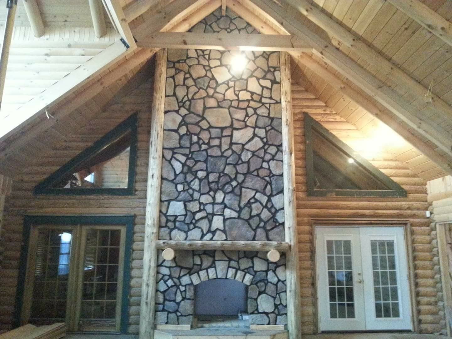 Rustic lodge interior with stone fireplace, wood beams, and French doors