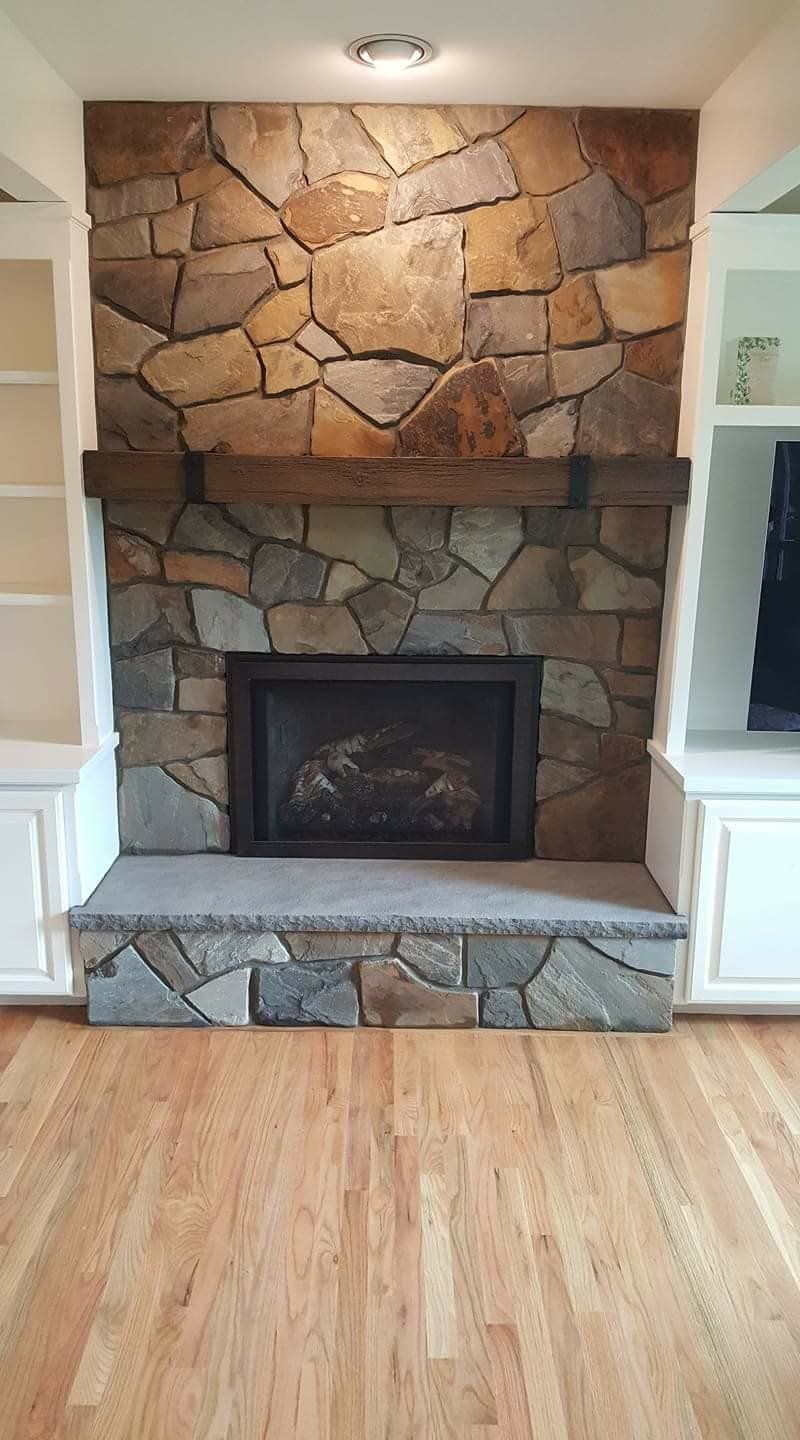 Stone fireplace with a black insert and wooden floor in a living room