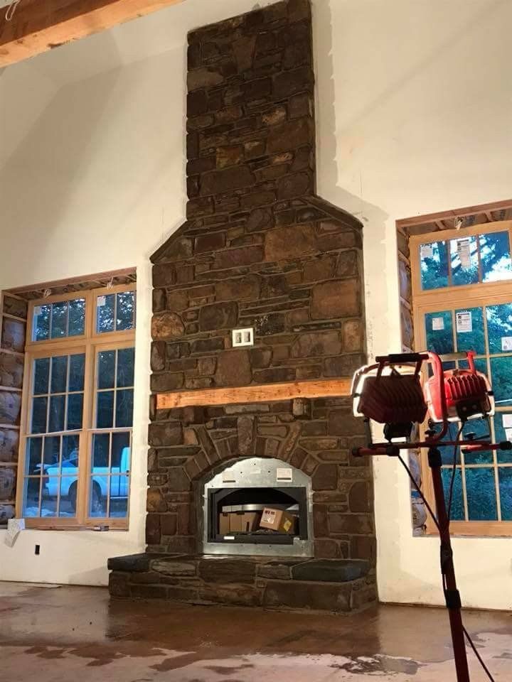 Stone fireplace with built-in oven in a room with blue-trimmed windows and a tripod light stand