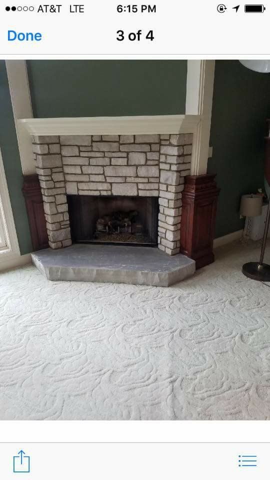 Stone fireplace with a gray hearth in a carpeted living room.