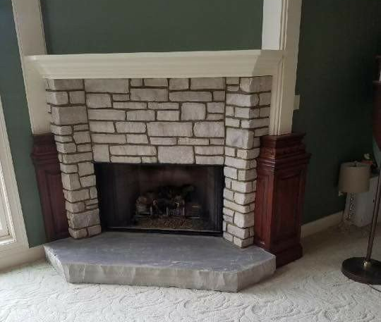 Stone fireplace with a white mantel and dark wood side cabinets in a living room