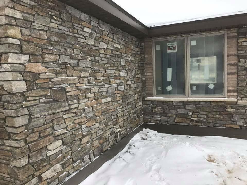 Stone exterior wall and window with snow-covered ground outside a house
