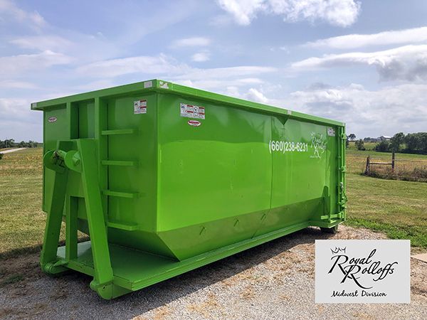 Two men shake hands beside a bright green dumpster at a house construction site.