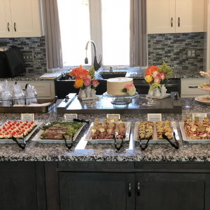Kitchen island with trays of assorted desserts and flower arrangements on a granite countertop