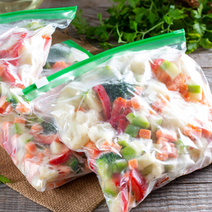 Plastic bags of chopped mixed vegetables with green zipper seals on a table