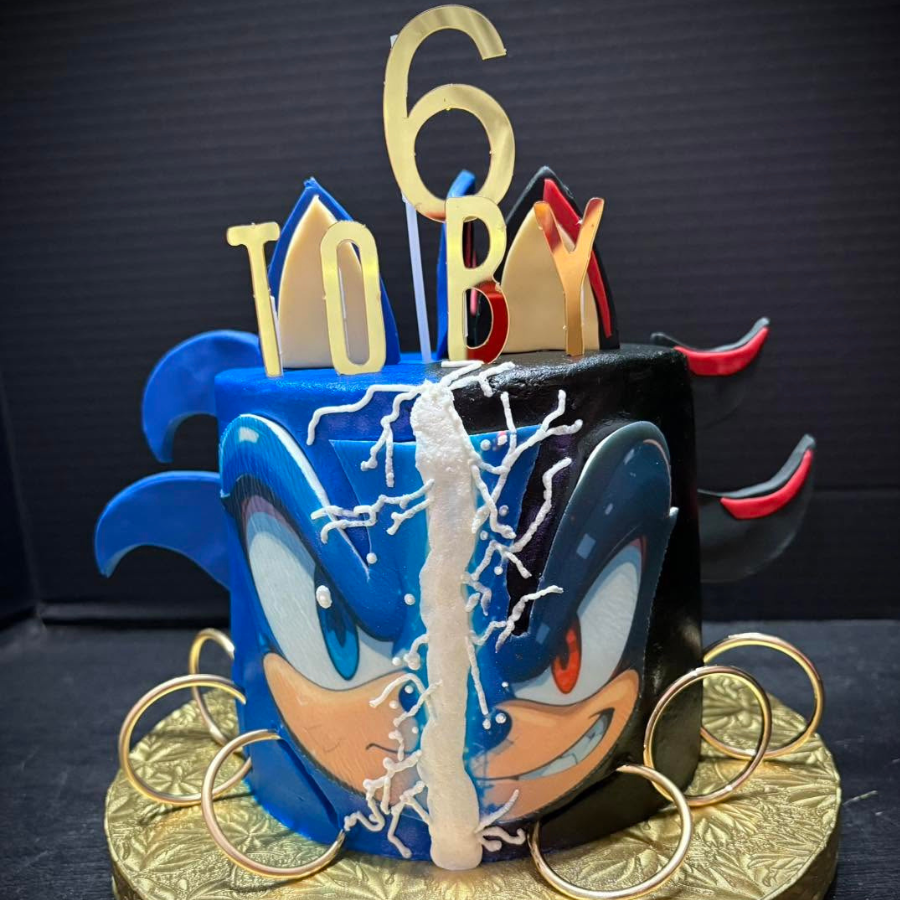 Sonic-themed birthday cake with blue icing, gold “6” topper, and red accents on a gold base