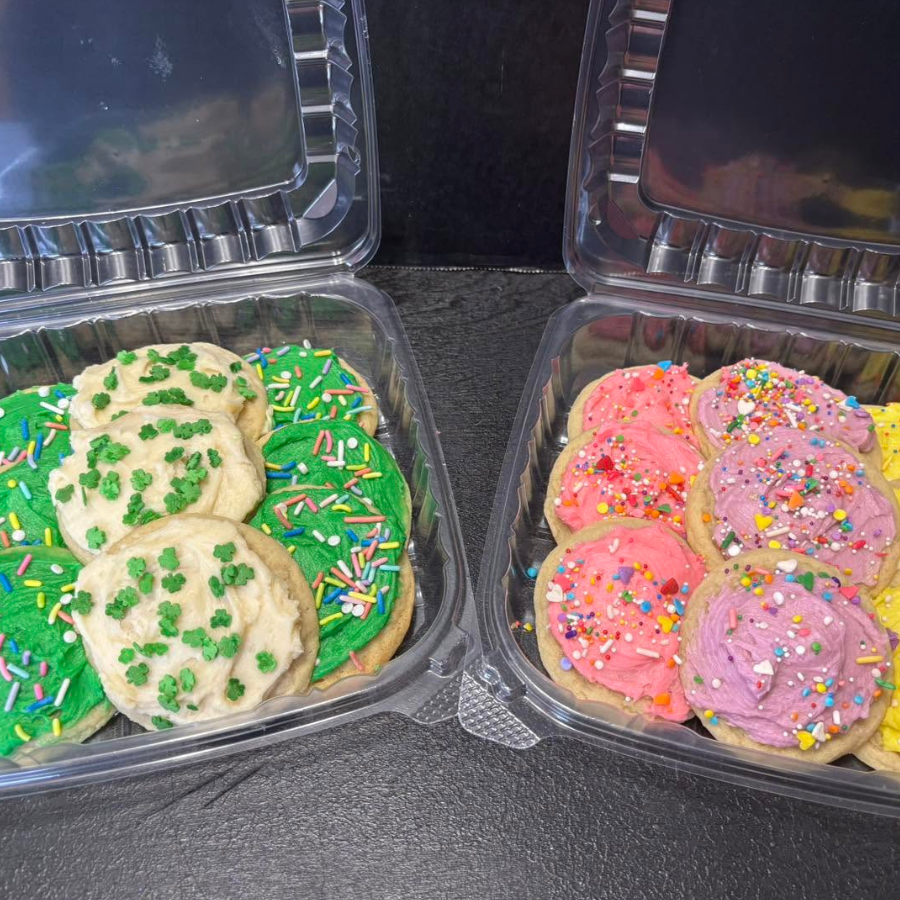 Two open cookie containers with frosted cookies: green sprinkles on left, pink and purple sprinkles on right.