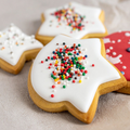 Star-shaped iced sugar cookies with colorful sprinkles on a linen surface