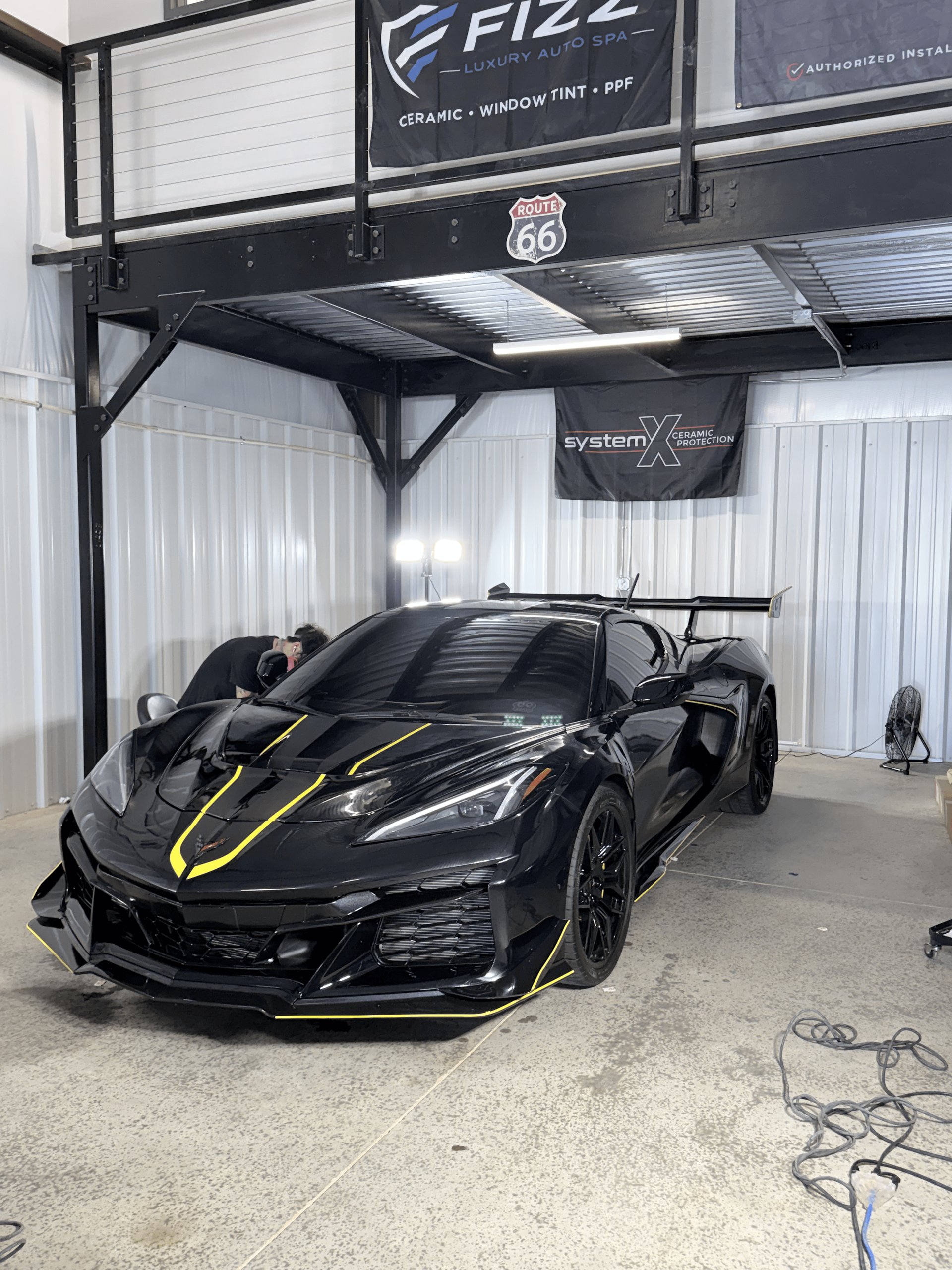 Black sports car with yellow accents in a garage-style detailing bay