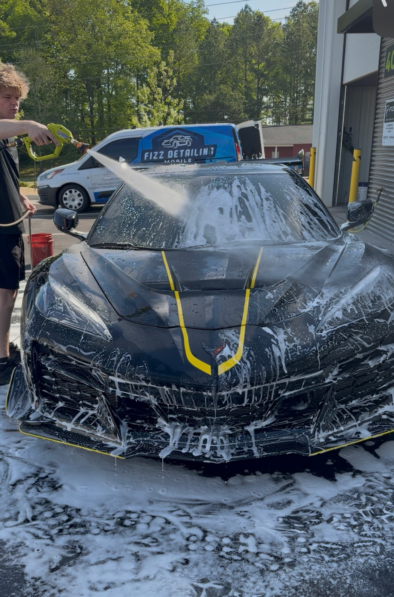 Black sports car with yellow accents in a garage-style detailing bay