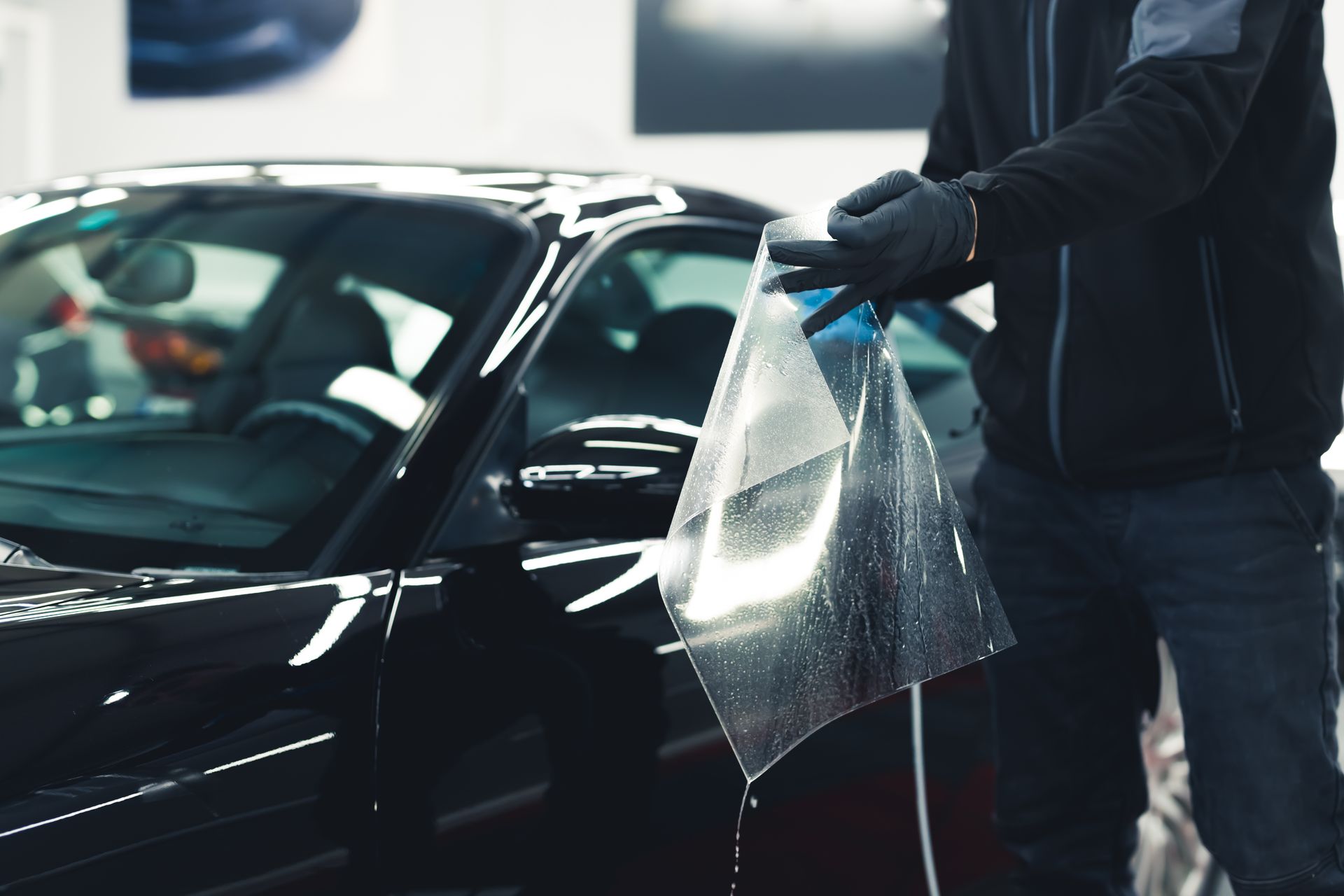 Front view of a black Ferrari with a yellow accent, wet from rain, being washed outdoors