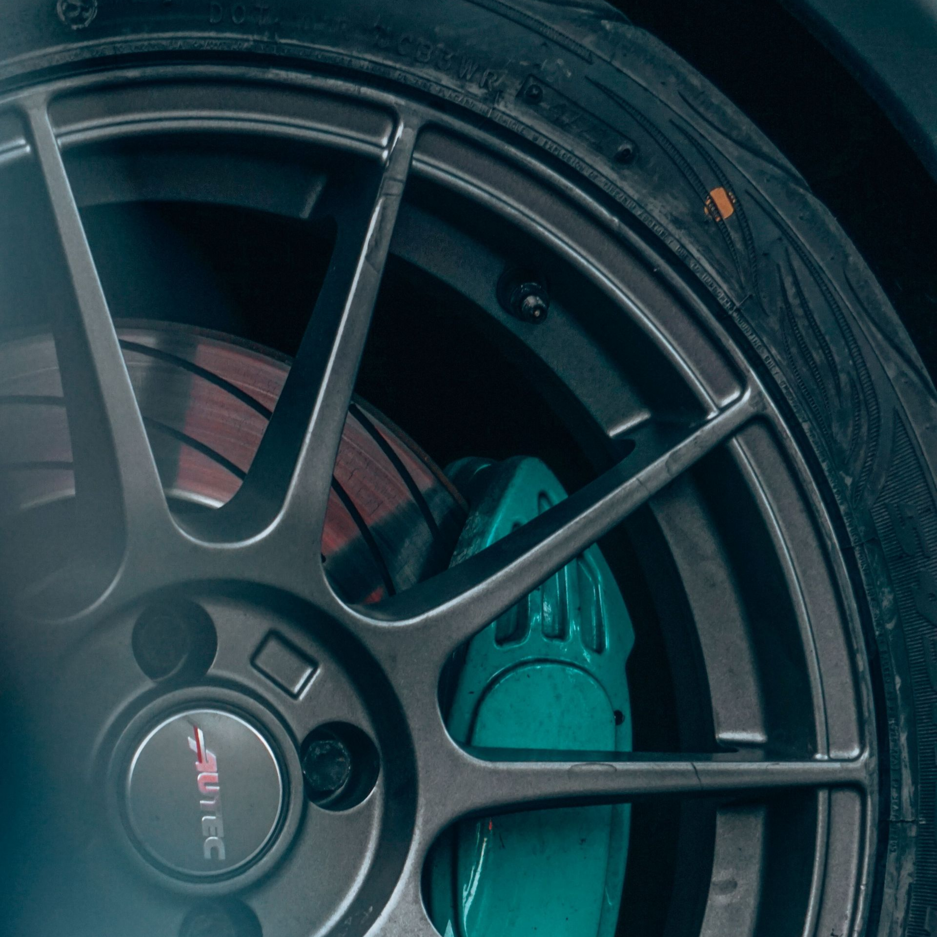 White Tesla Model S sedan on a white background, front three-quarter view with black wheels and teal headlights