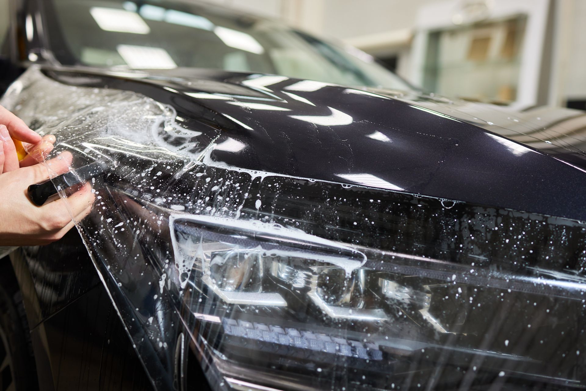 Front view of a black Ferrari with a yellow accent, wet from rain, being washed outdoors