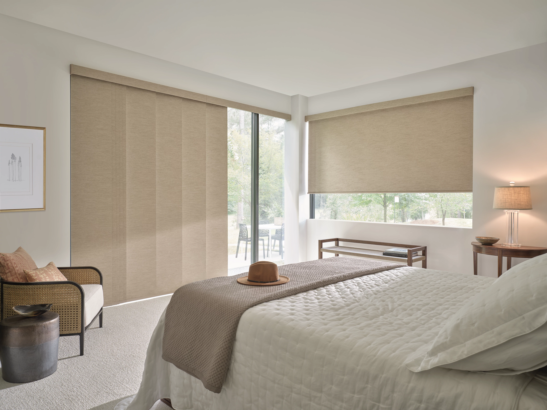 Bright bedroom with a bed, tan blinds, window, and a side table lamp near a sliding door.