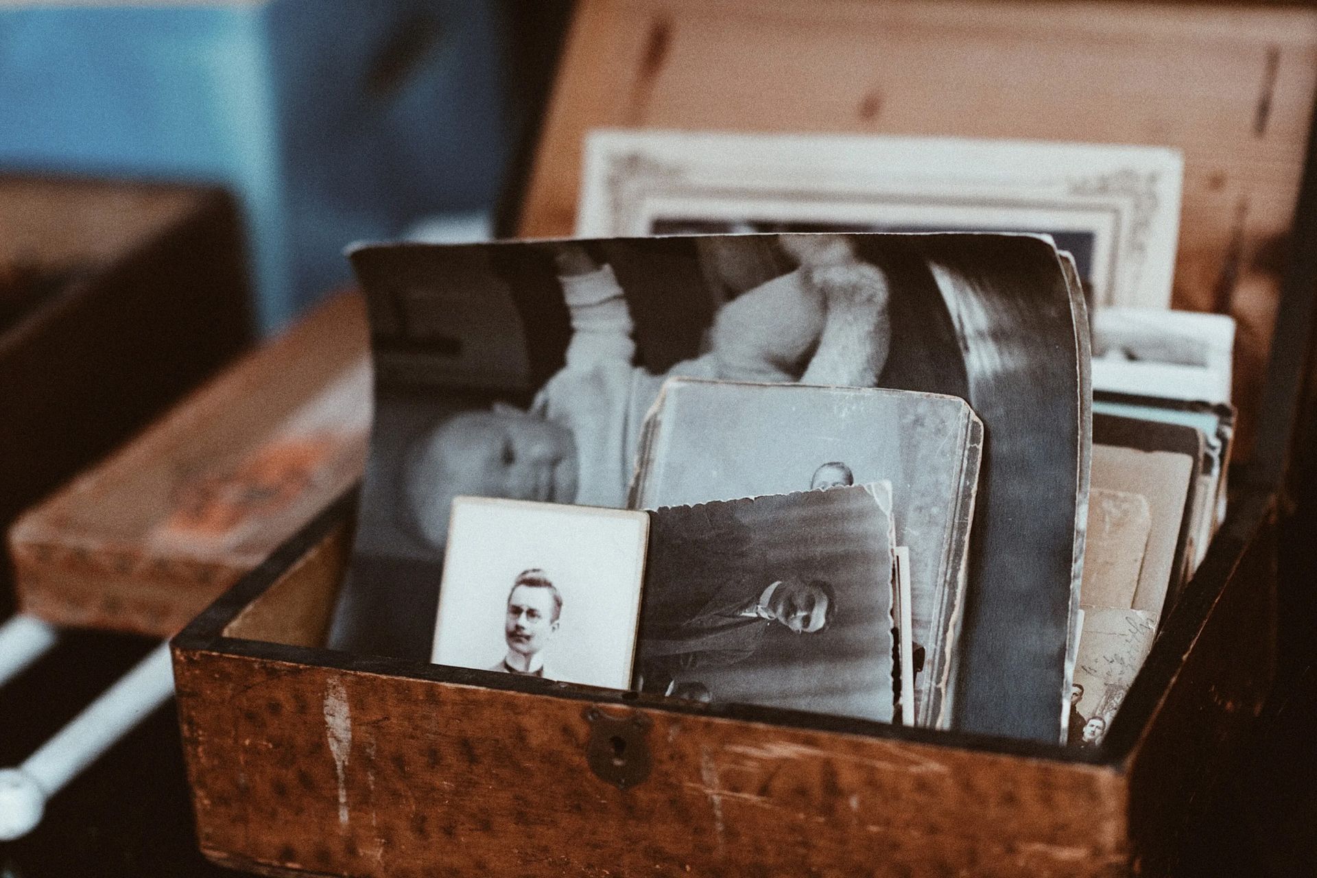Open wooden box filled with vintage black-and-white photographs and postcards