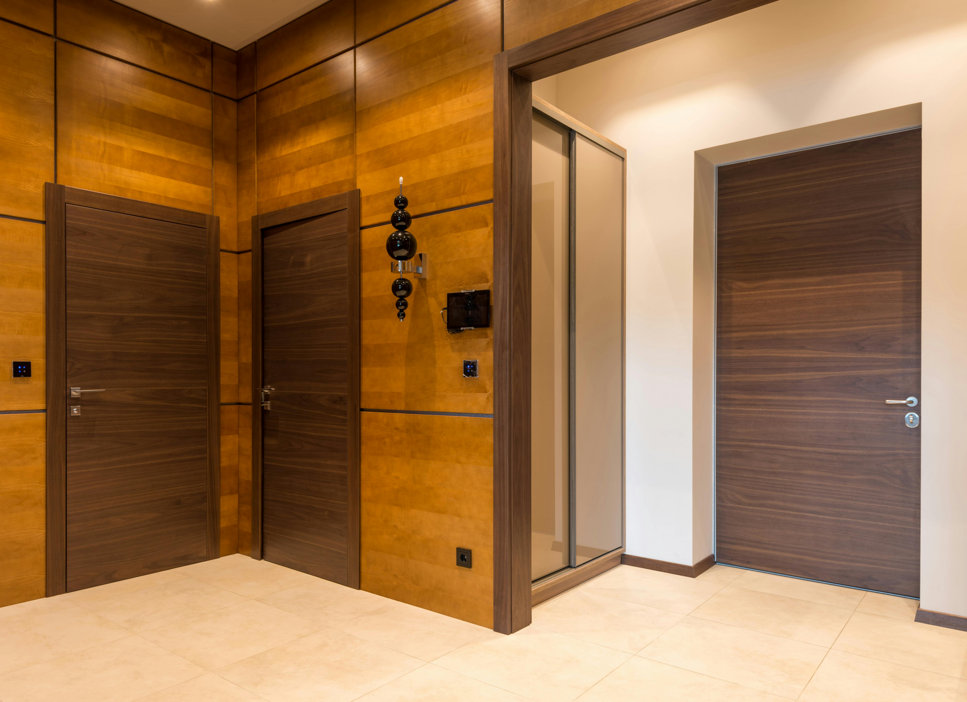 Wooden entryway with three doors: two dark brown, one light brown leading to a closet.
