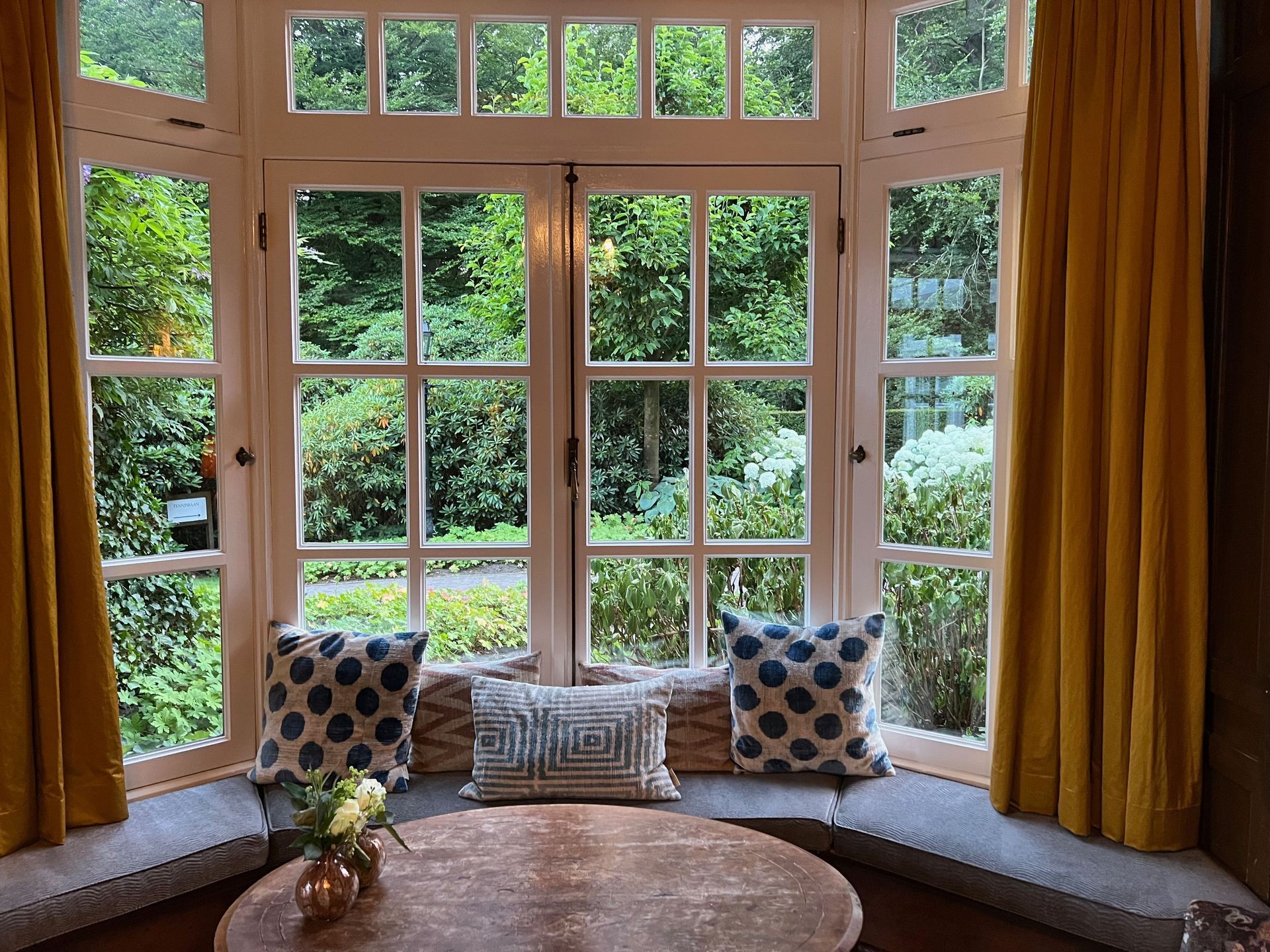 Two white-framed windows with black grids on a yellow wall, casting shadows.