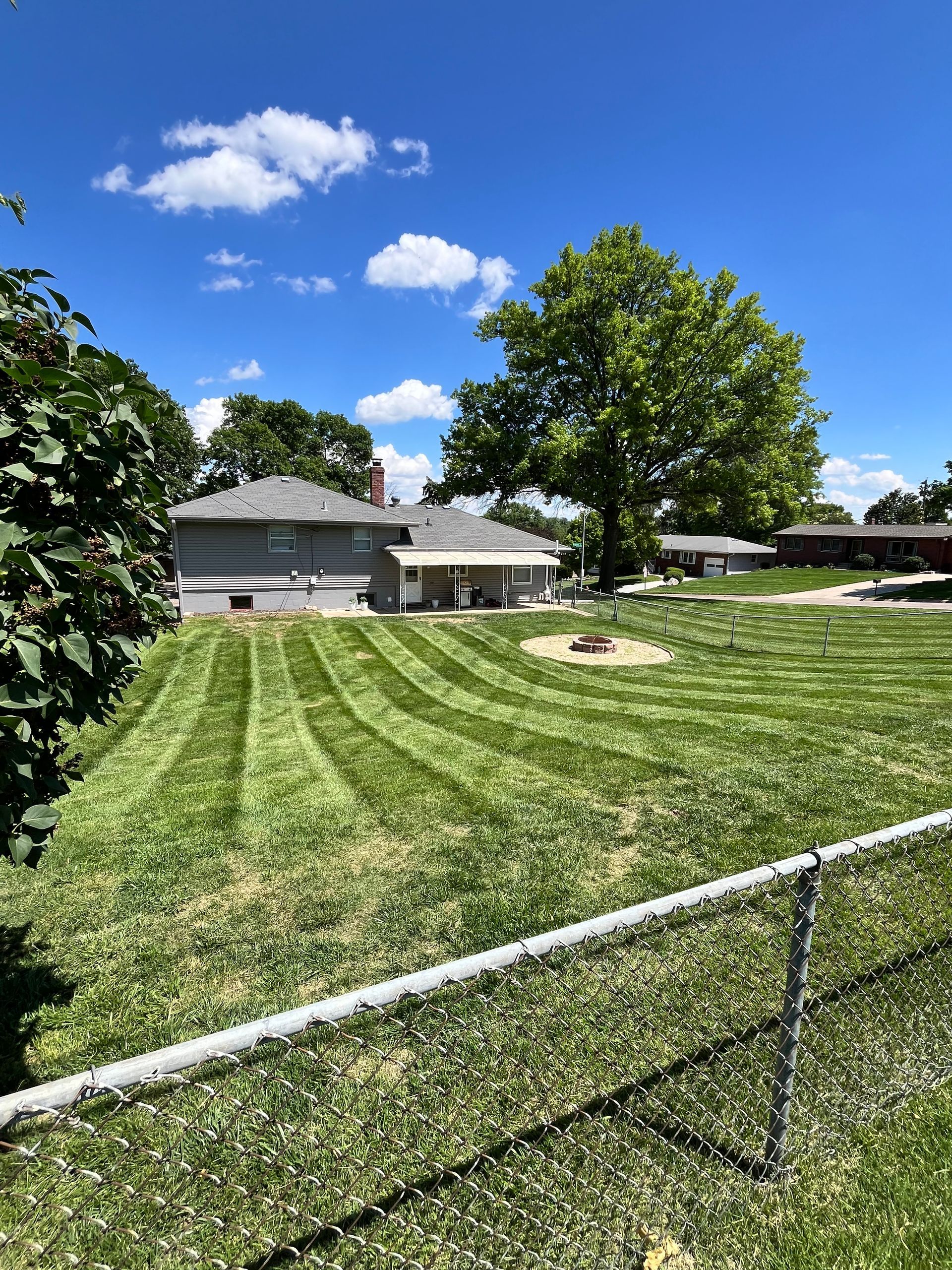A Fence Surrounds a Lush Green Lawn in Front of a House