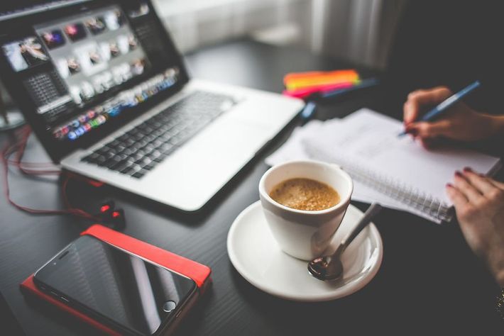 A person is sitting at a desk with a cup of coffee and a laptop.