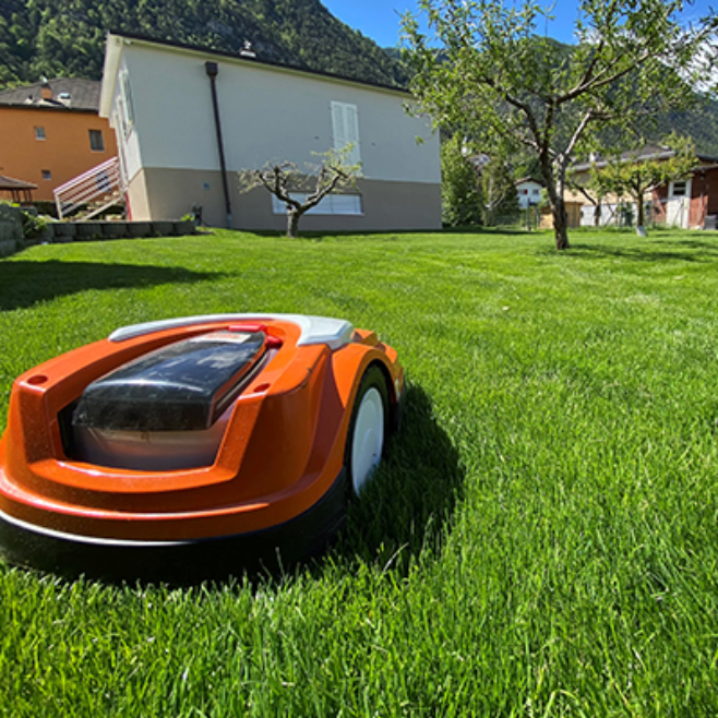 Une tondeuse à gazon robotisée est assise sur une pelouse verte luxuriante