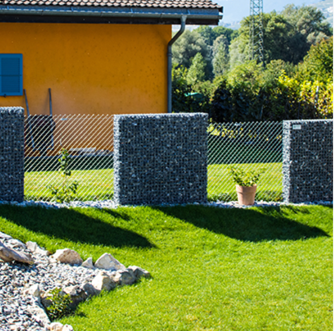 Une clôture entoure une pelouse verte luxuriante devant une maison orange