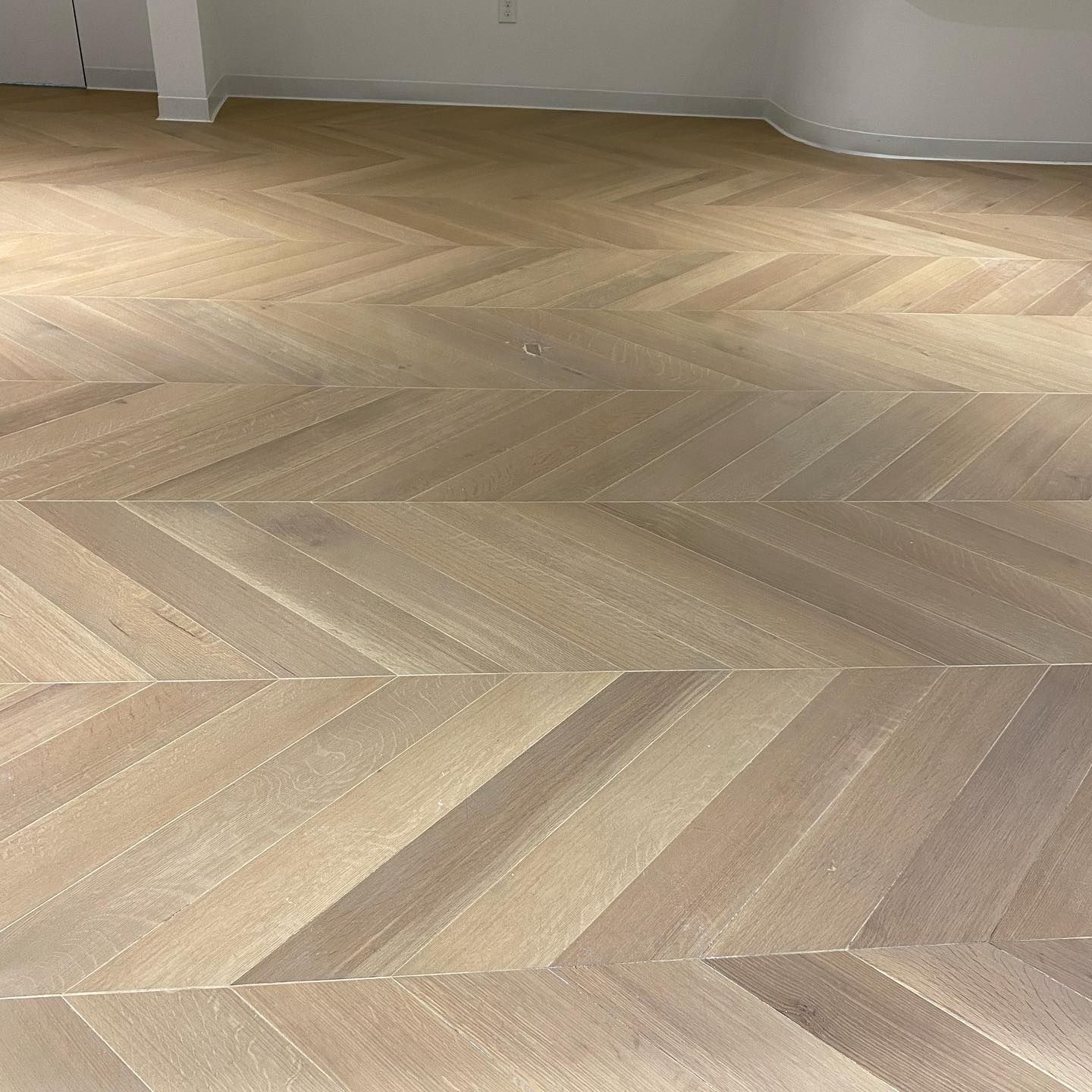 A close up of a wooden floor with a herringbone pattern.