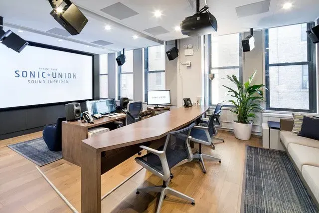 A conference room with a long table and chairs and a large screen.