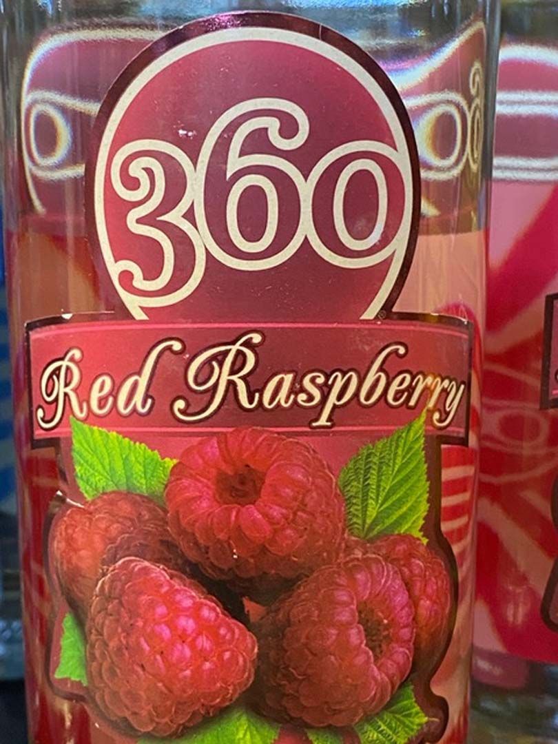 A bottle of red raspberry juice with a picture of raspberries on the label.