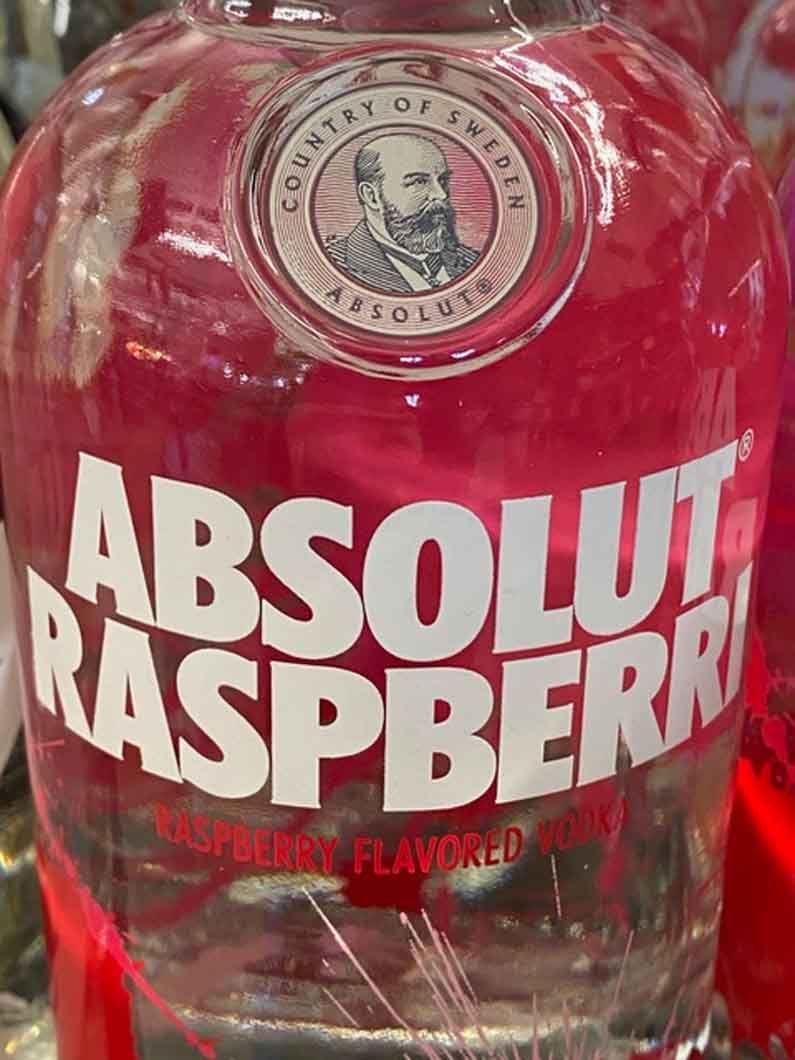 A close up of a bottle of absolut raspberry vodka.