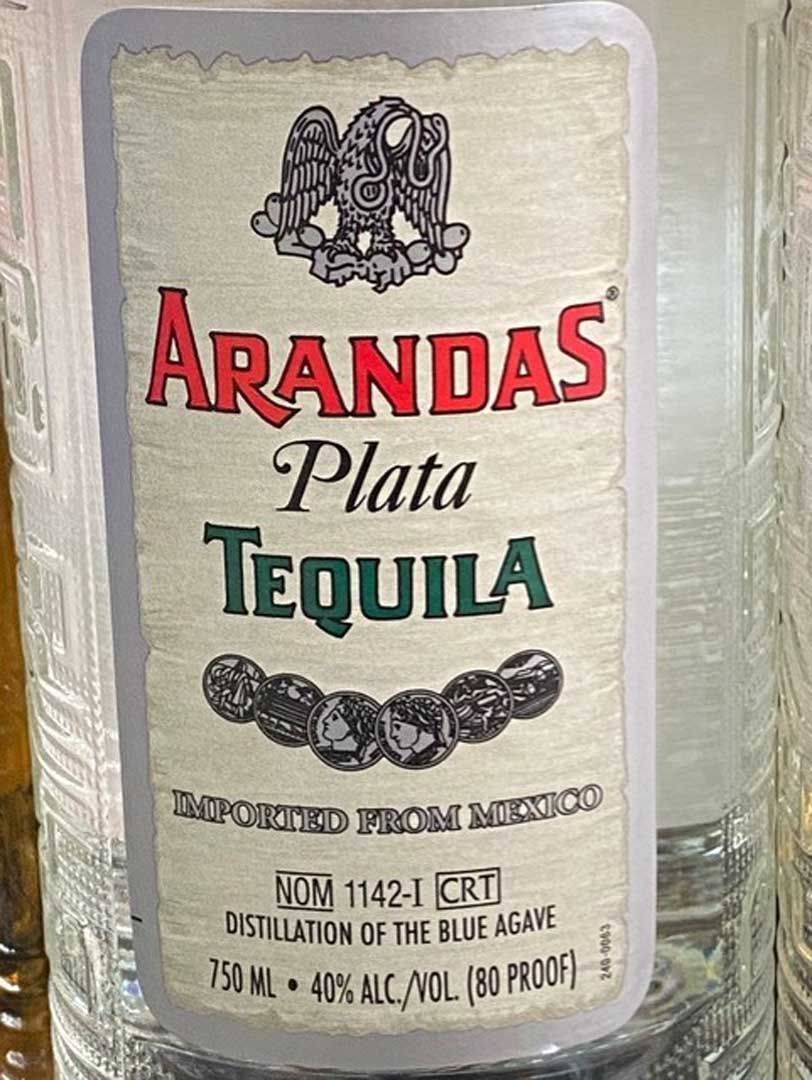 A bottle of arandas plata tequila is sitting on a wooden table.