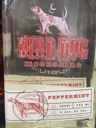 A bottle of bird dog moonshine peppermint is sitting on a table.