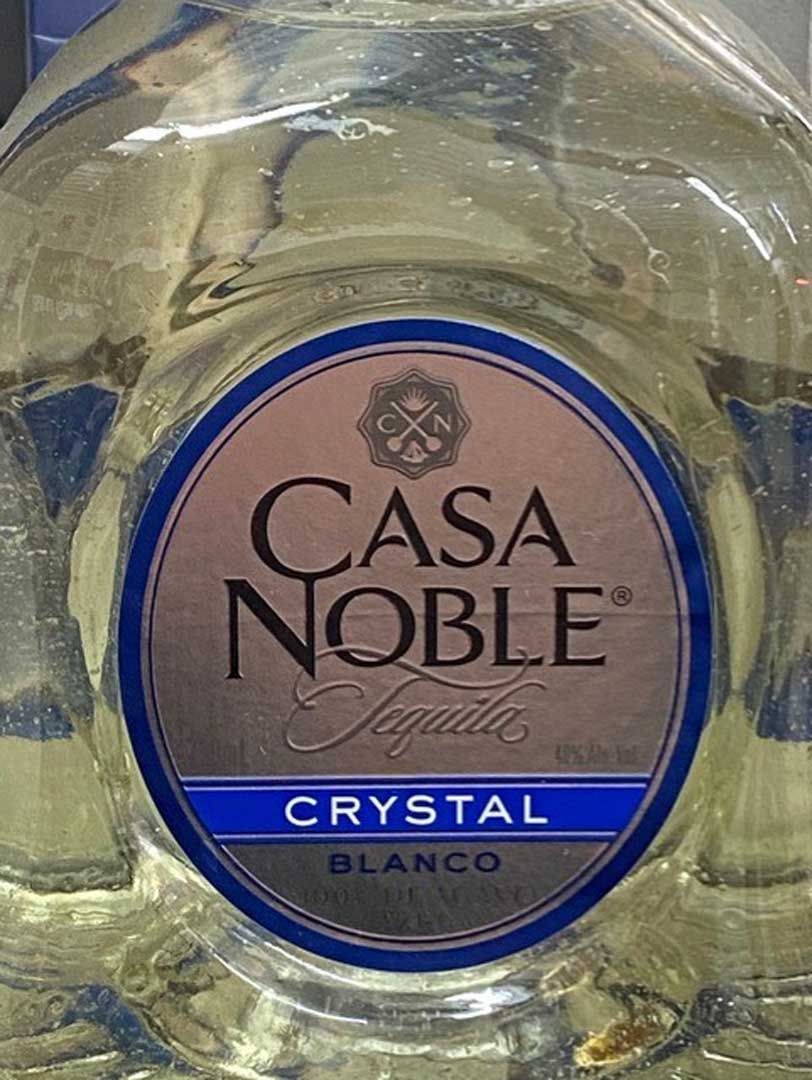 A bottle of casa noble crystal tequila is sitting on a table.