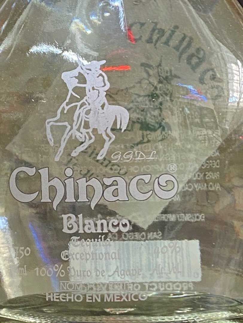 A bottle of chinaco blanco tequila with a cowboy on a horse on the label.