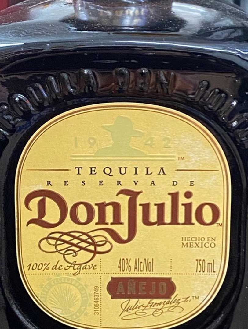 A bottle of don julio tequila is sitting on a table.
