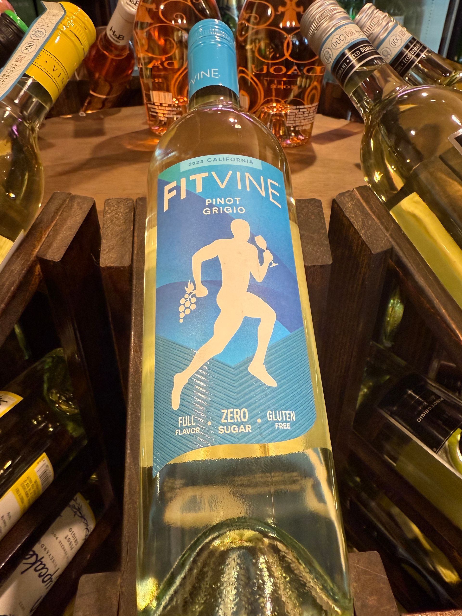 Bottle of Fitvine Pinot Grigio wine with a running figure on a blue label, in a wooden crate.