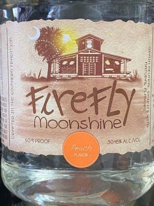 A close up of a bottle of firefly moonshine peach flavor.