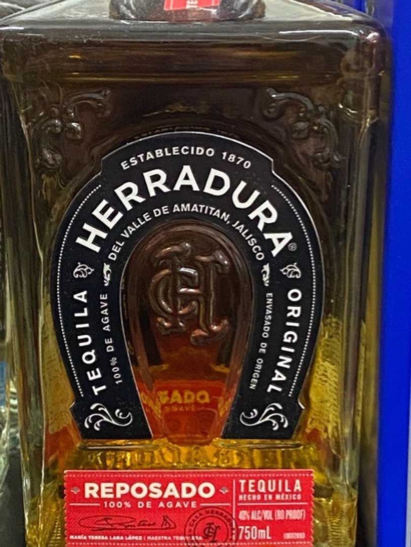 A bottle of herradura reposado tequila with a horseshoe on it.