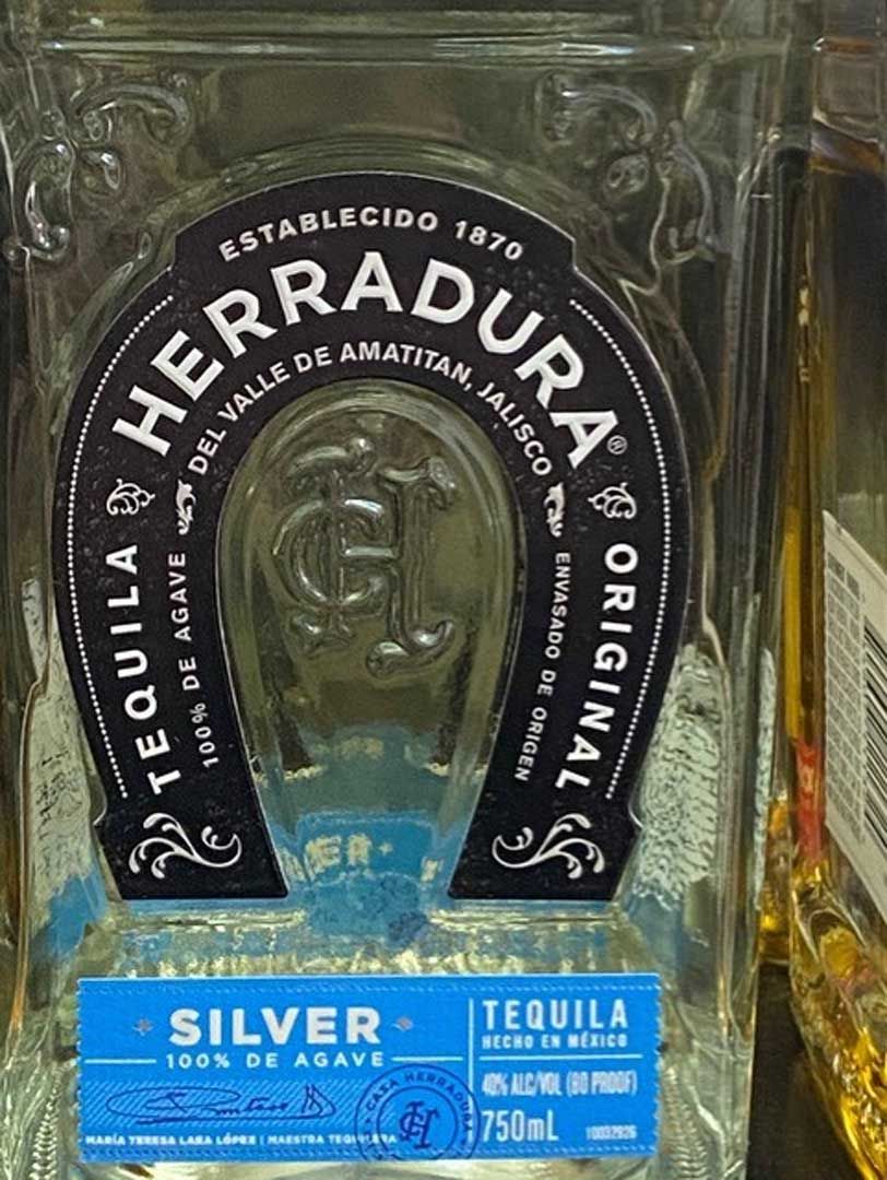 A bottle of herradura silver tequila with a horseshoe on the label.