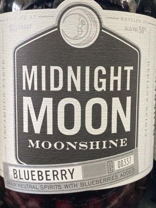 A close up of a bottle of midnight moon blueberry moonshine.