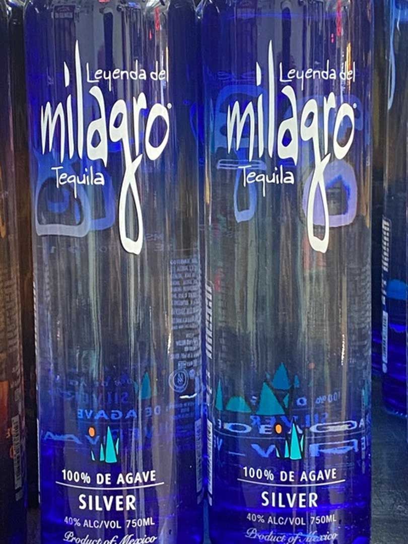 Two bottles of milagros silver tequila are sitting next to each other on a table.