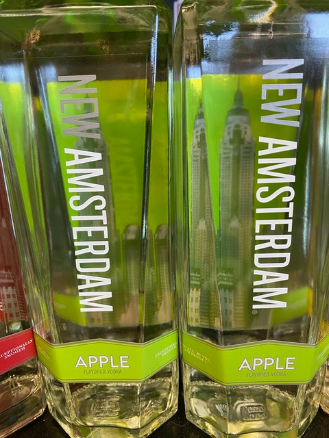 Two bottles of new amsterdam apple vodka are sitting on a table.
