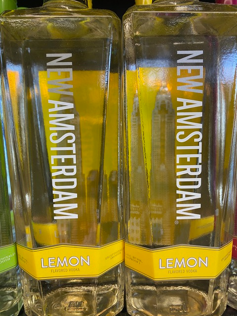 Two bottles of new amsterdam lemon vodka are sitting next to each other.