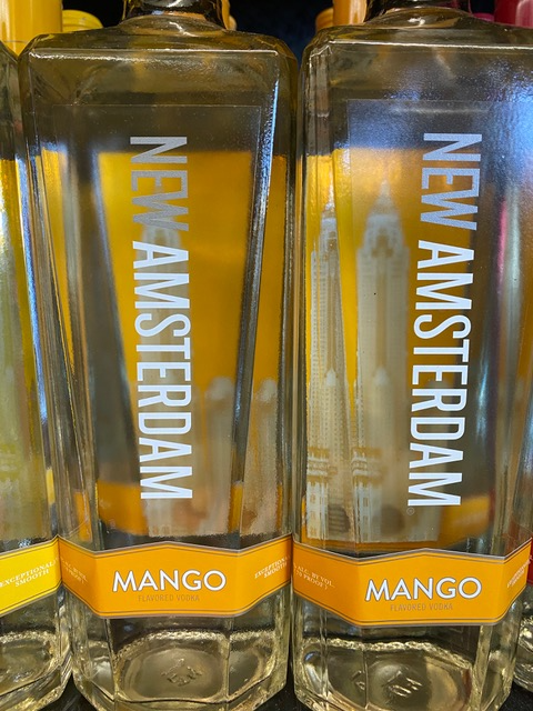 Three bottles of new amsterdam mango vodka are lined up on a shelf.