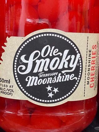 A bottle of ole smoky tennessee moonshine cherries is sitting on a table.