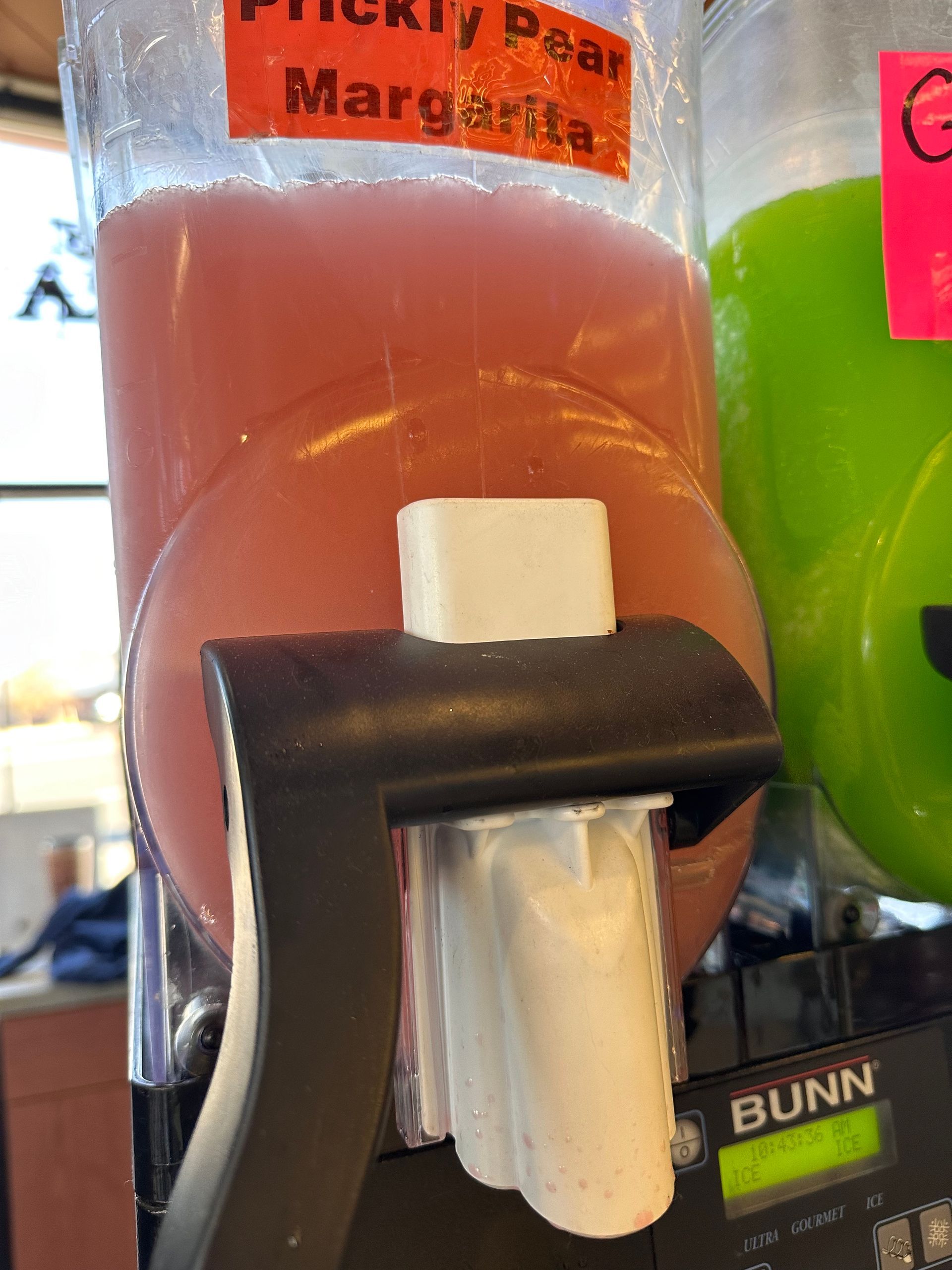A bunn drink dispenser filled with pink and green drinks