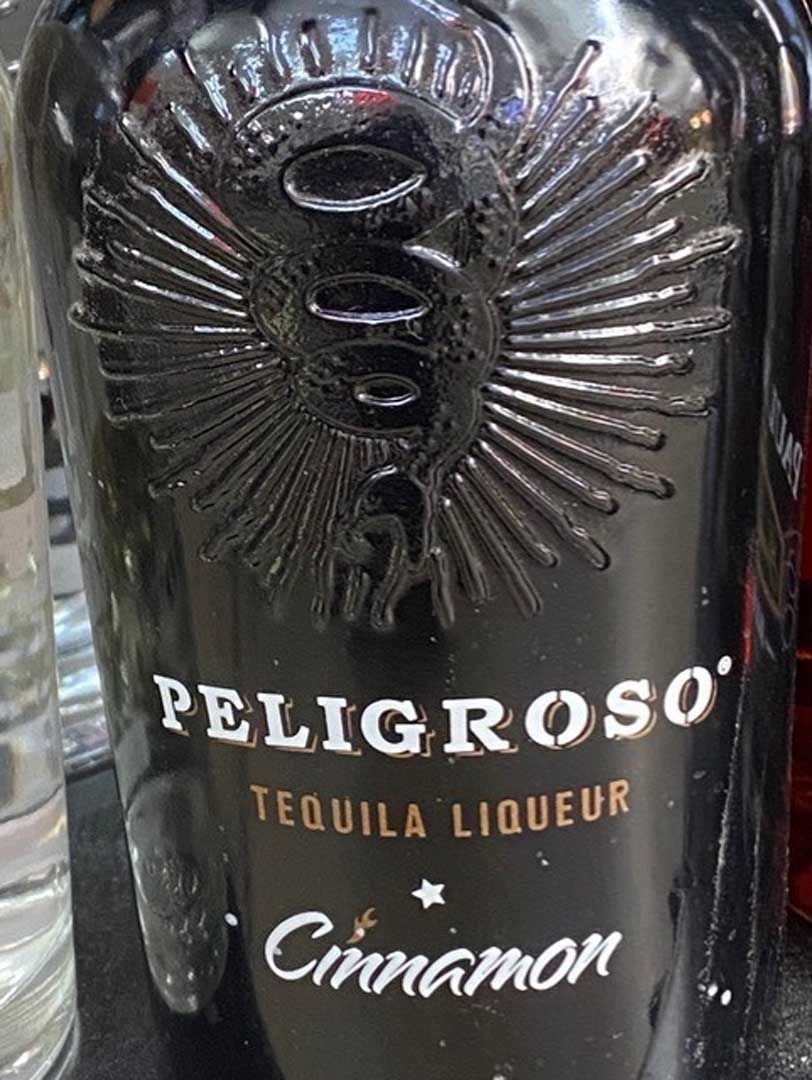 A bottle of peligroso tequila liqueur cinnamon is sitting on a table.
