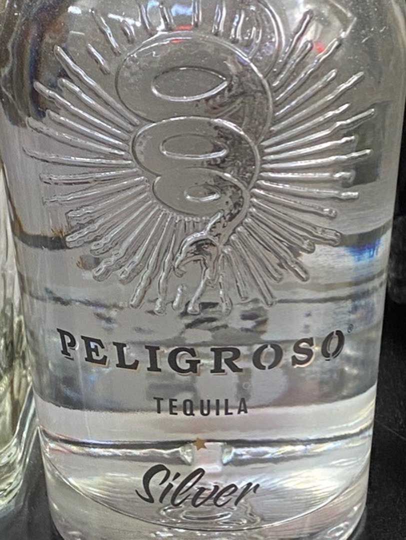 A bottle of peligroso silver tequila is sitting on a table.