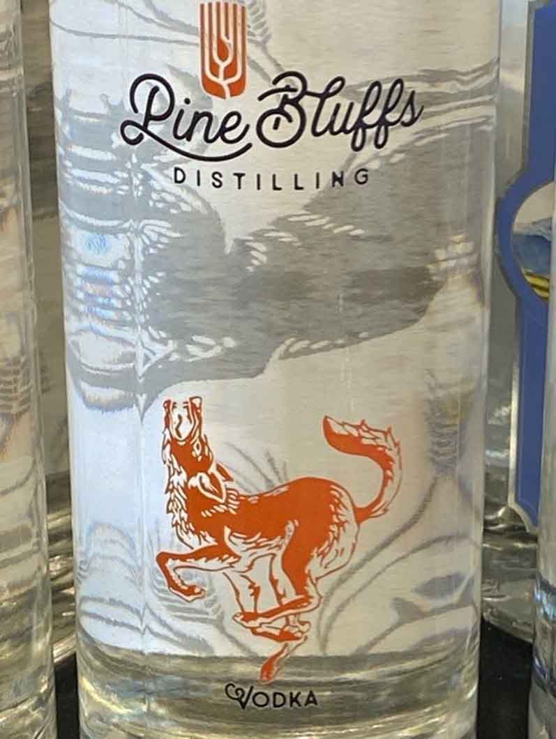 A bottle of pine bluffs distilling vodka with a wolf on the label