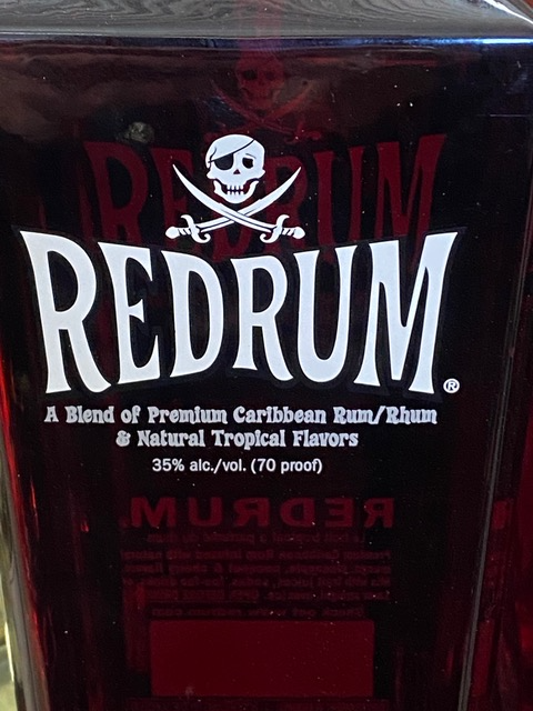 A bottle of redrum with a skull and crossbones on the label