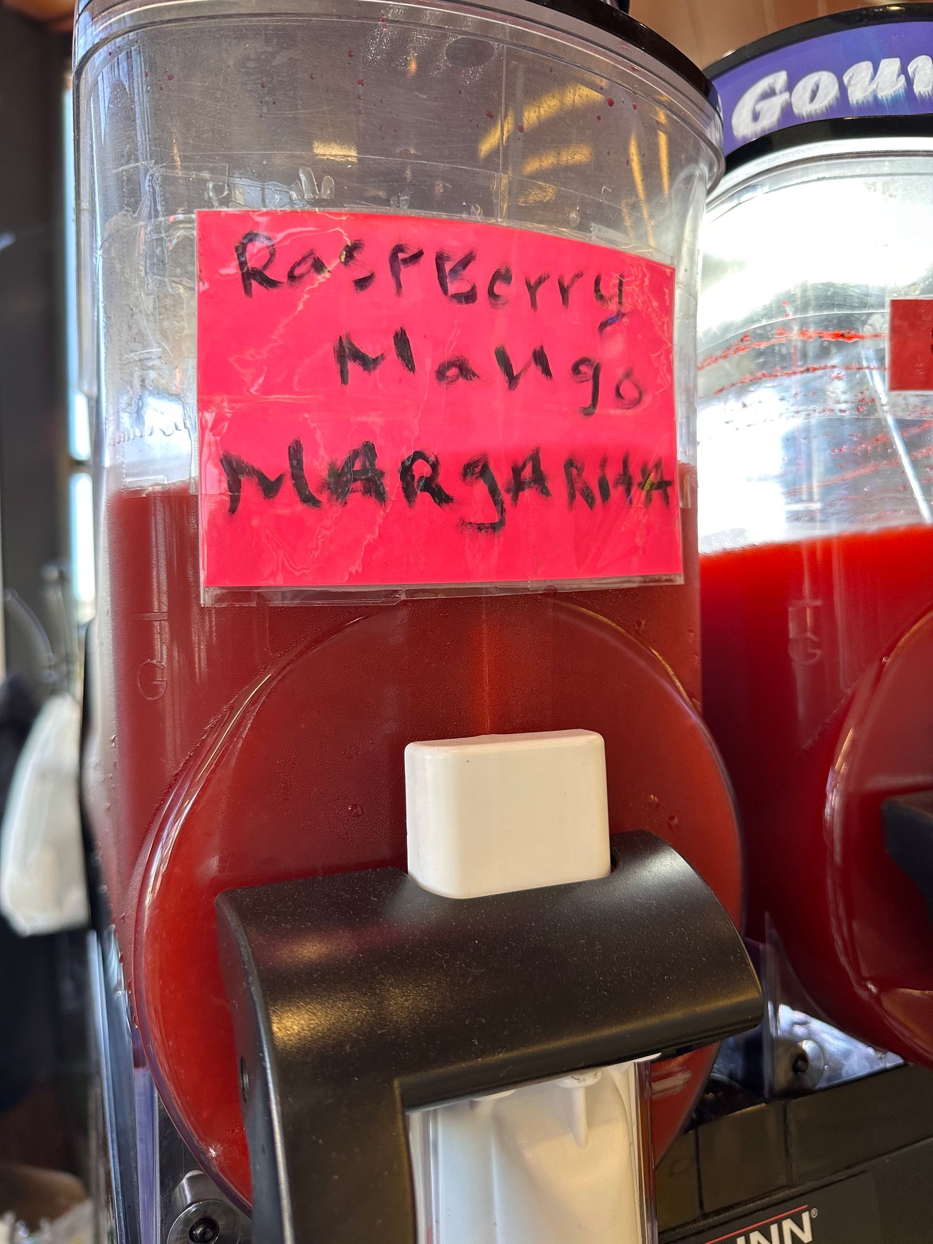 A raspberry mango margarita is being made in a machine